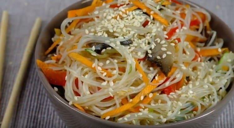 Riegue la ensalada con salsa cocida en una sartén, mezcle y espolvoree con semillas de sésamo.