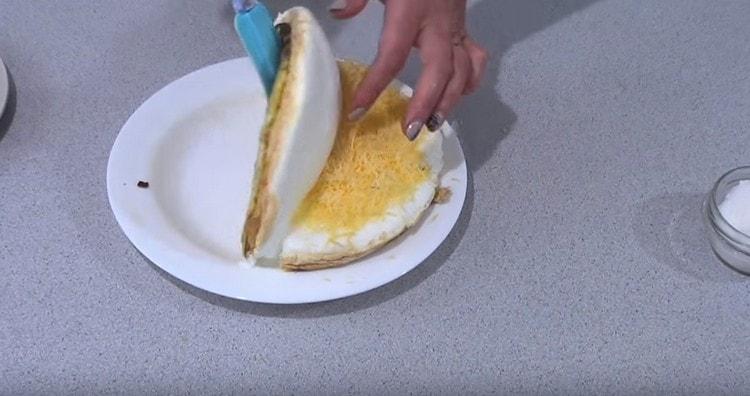 coupez soigneusement l'omelette, couvrez avec la moitié libre celle sur laquelle il y a du fromage.