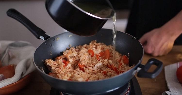 Ajouter le bouillon au safran dans la poêle avec la future paella.