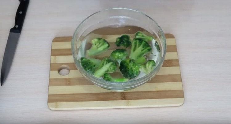 Dompel de bevroren broccoli in een kom met water.
