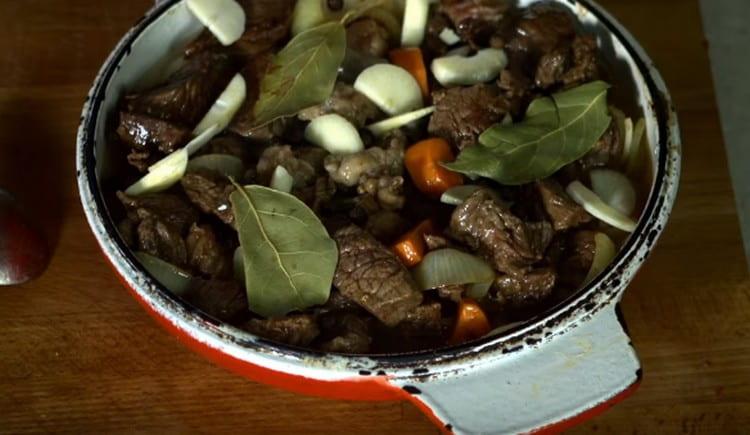 Ajoutez la viande frite aux légumes, ajoutez l'ail, la feuille de laurier, les épices.