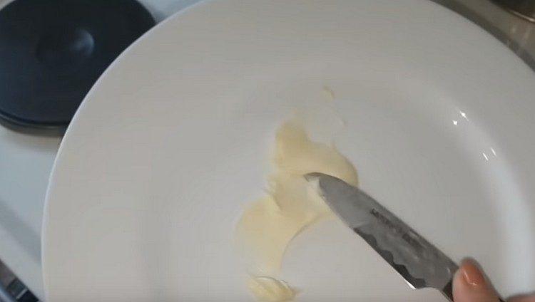 Graisser une assiette pour les crêpes avec du beurre.