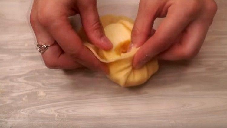 Mettez la moitié de la pomme au centre de chaque gâteau et ramassez la pâte avec un sac.