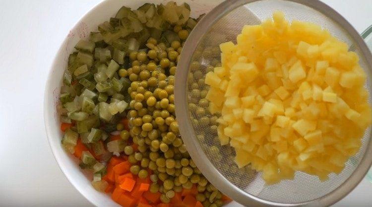 Ajouter les pommes de terre refroidies et les pois en conserve à la salade.