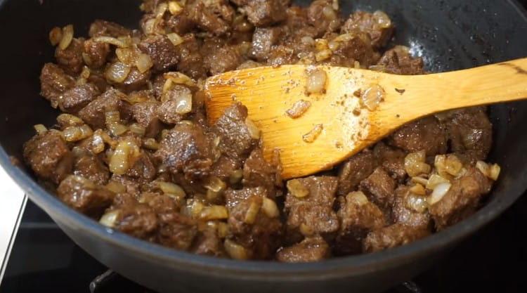 Add the onions to the meat and fry all together.