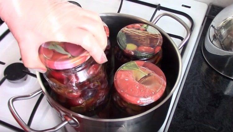 We put jars with plums in a pan and sterilize.