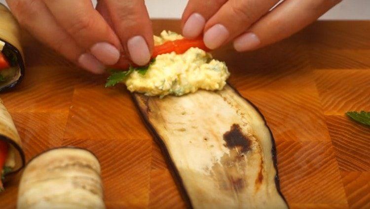 Sur une tranche d'aubergine frite, mettez une petite farce, une feuille de persil et une tranche de tomate.