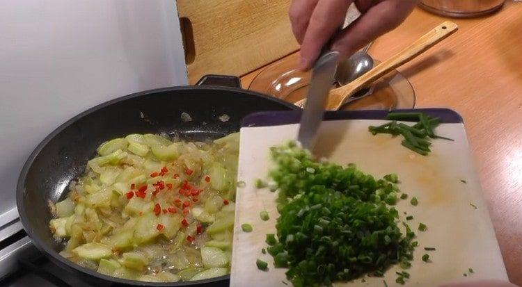 Ajouter le piment haché et l'oignon vert dans la poêle.