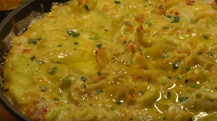 Les courgettes presque finies avec des œufs dans une casserole peuvent également être saupoudrées de fromage râpé.