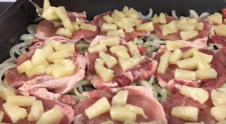 We lay the meat on top of the onion, and lay on it slices of pineapple.