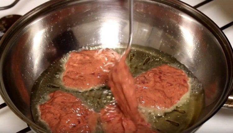 We spread the dough with a spoon into the pan, forming round cutlets.