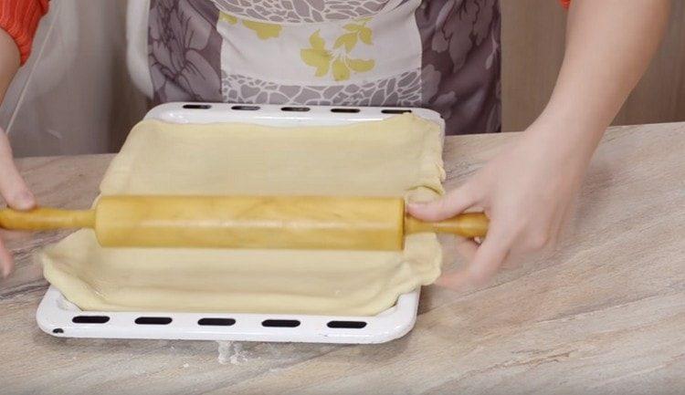 We shift the dough onto a baking sheet and form the base of the pie.