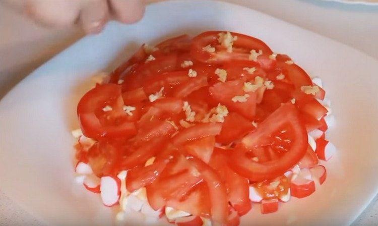 Répartissez l'ail haché sur les tomates et faites un filet de mayonnaise.