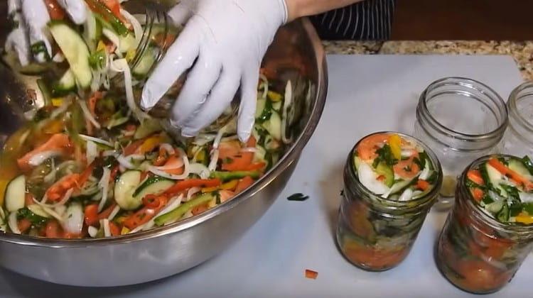 Putting pepper on the bottom of each jar, fill them with salad.