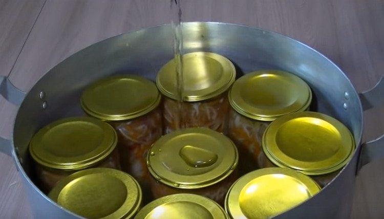 We put the jars in the pan, cover with lids, pour water and sterilize the salad.