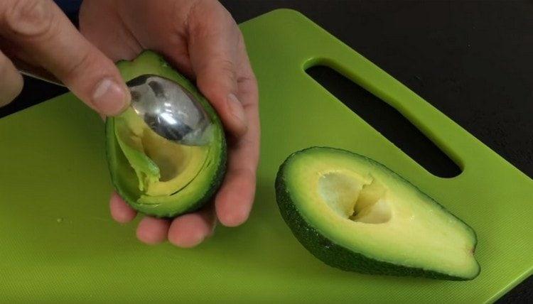 Selecteer voorzichtig met een lepel het vruchtvlees uit de avocado.