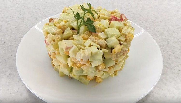 une telle salade avec des bâtons de crabe et des craquelins peut être servie joliment, décorée avec un anneau de pâtisserie.