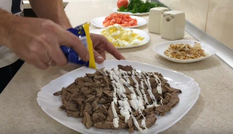 On étale le foie avec la première couche de salade, on le graisse légèrement avec de la mayonnaise.