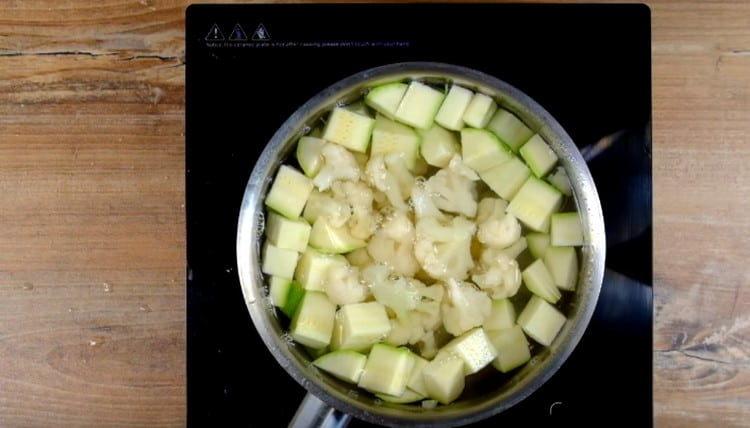 In boiling water, spread the zucchini and cauliflower inflorescences sliced ​​in slices.