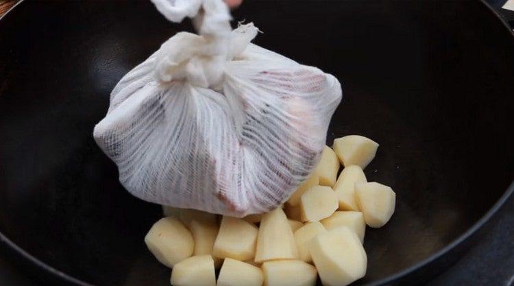 In the cauldron we lay out coarsely chopped potatoes and fish heads in gauze.