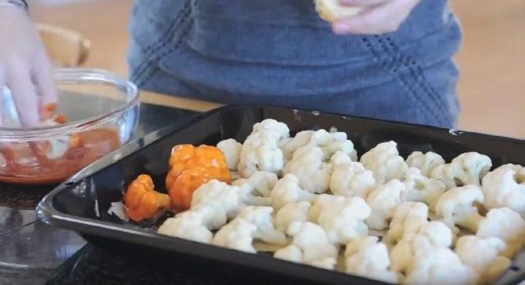 We take out a baking sheet, dip each inflorescence in tomato sauce and return to the baking sheet.