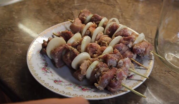 We string the meat alternately with onions on wooden skewers.