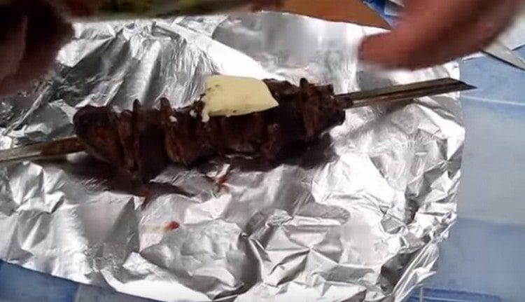 We lay out each skewer on a sheet of foil, put a piece of butter on top of the liver.