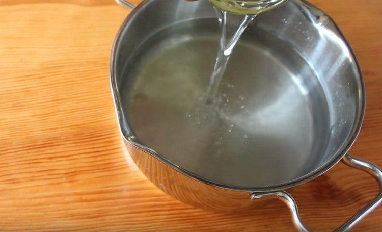 Pour water from a can into a pan.
