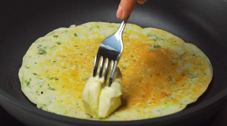 Retournez la crêpe de l'autre côté et lubrifiez-la immédiatement avec un morceau de beurre.