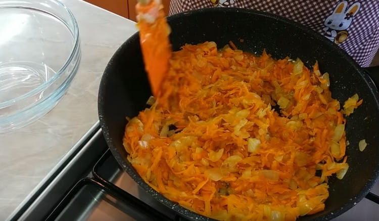 Agregue las zanahorias a las cebollas y pase las verduras juntas.