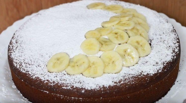 Saupoudrer le gâteau à la banane fini avec le sucre glace et décorer avec des tranches de banane.