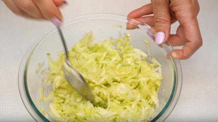 trois courgettes sur une râpe. salez et mélangez.