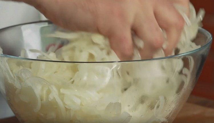 couper l'oignon en rondelles et pétrir avec du sel.