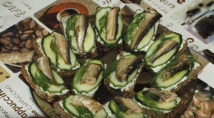 We decorate sandwiches with sprats and a fresh cucumber with a sprig of dill.