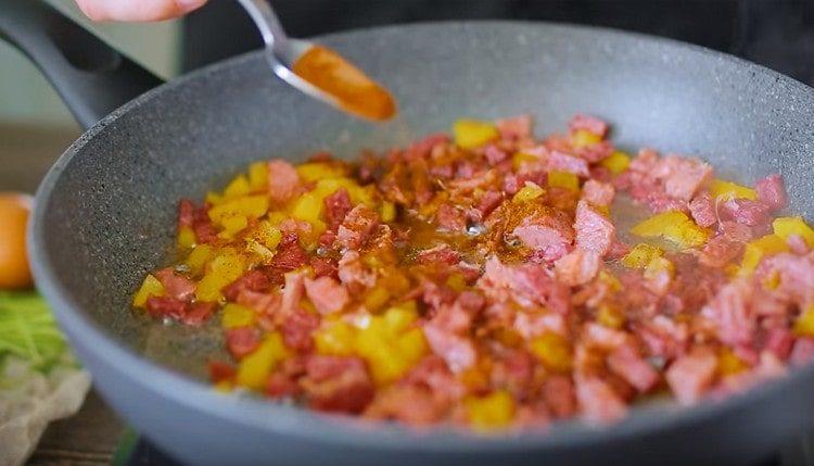 Kobasicu pržite sa šunkom, dodajte sitno sjeckanu slatku papriku i papriku.