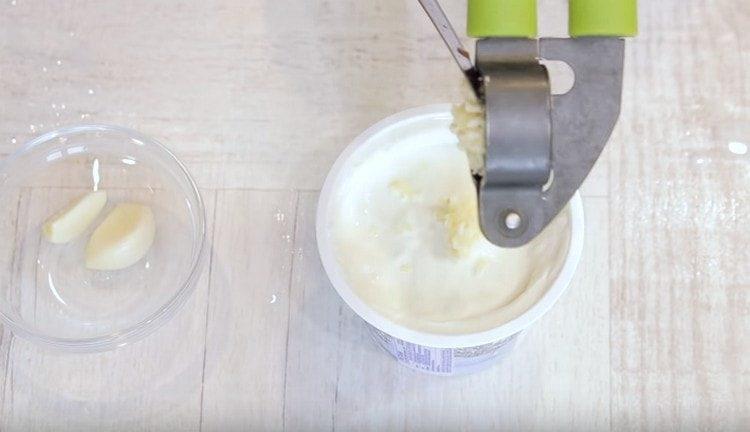 Exprima el ajo en la crema agria y mezcle.