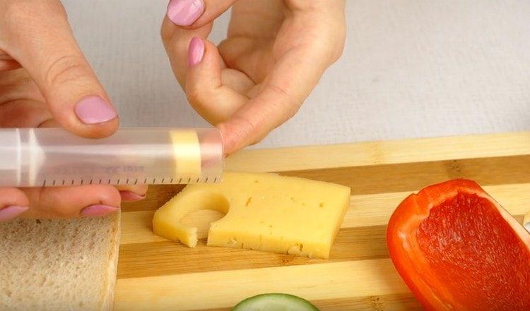 Squeeze a circle out of a slice of cheese with a syringe.