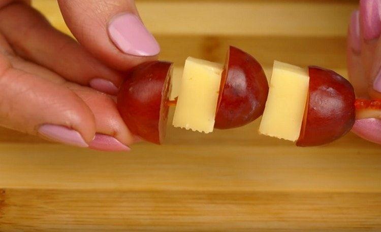 Mettez alternativement une brochette de raisins et des morceaux de fromage.