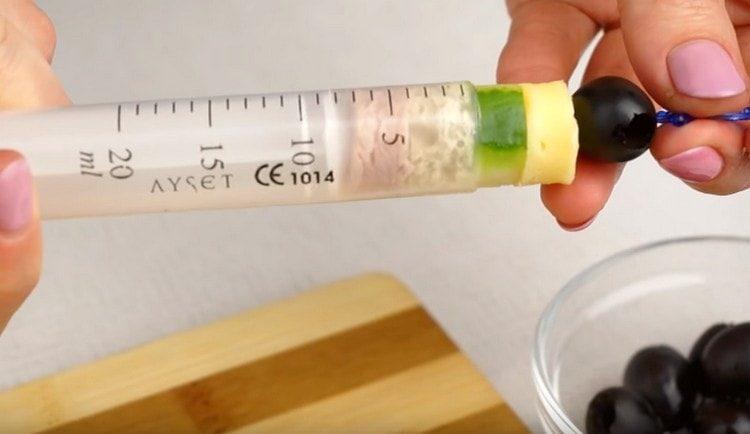 put olive on a skewer and thread it into the ingredients in a syringe.