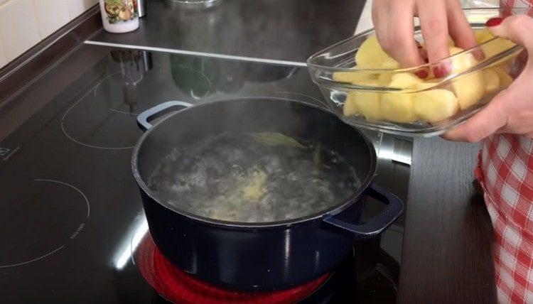 Nous nettoyons les pommes de terre, les coupons en morceaux et les mettons dans de l'eau bouillie.
