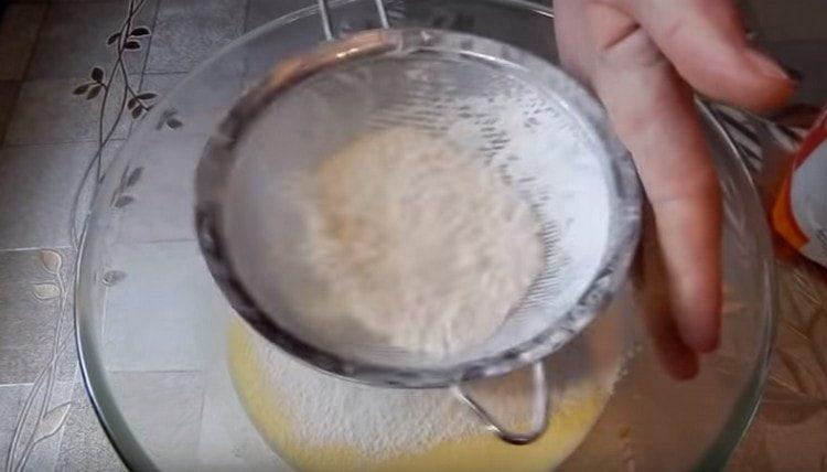 Tamiser la farine dans la masse d'œufs.