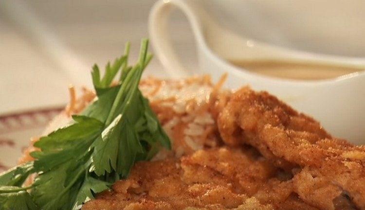 Chuletas de cerdo cocinado en una sartén, servido con una guarnición de arroz con fideos y salsa.