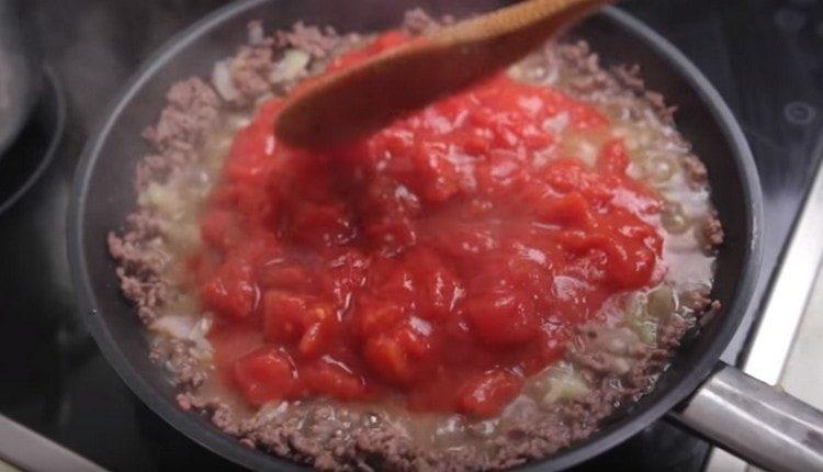 We shift the vegetables to the minced meat, add the tomatoes in our own juice.