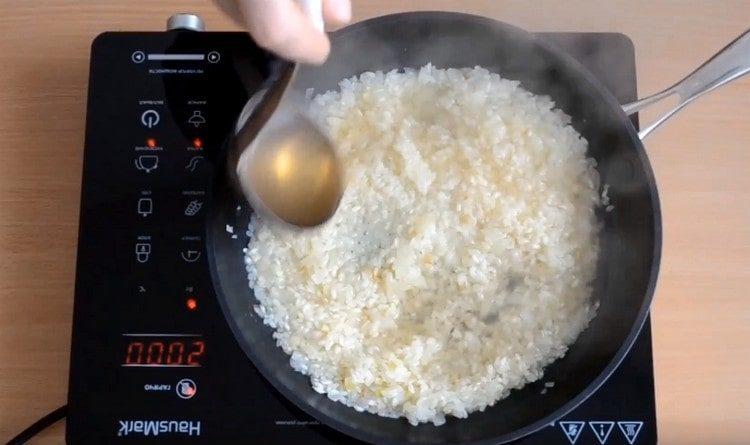 Se agrega un cucharón al caldo de arroz con champiñones.