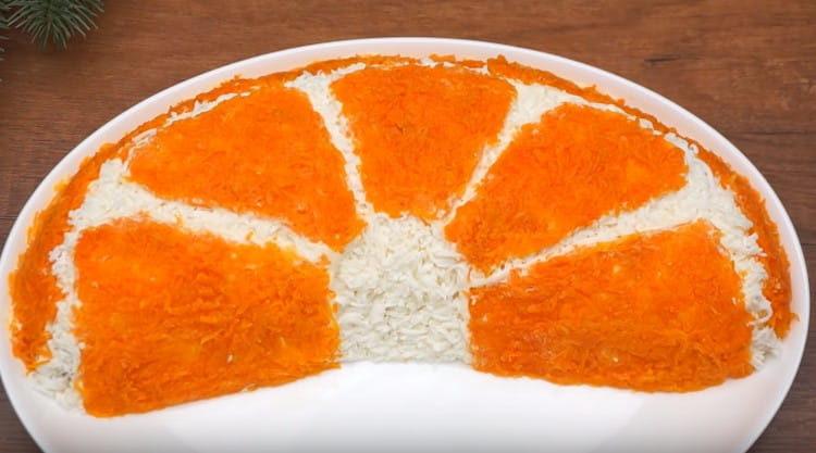 Decoramos la ensalada con zanahorias, y la rodaja de naranja está lista.
