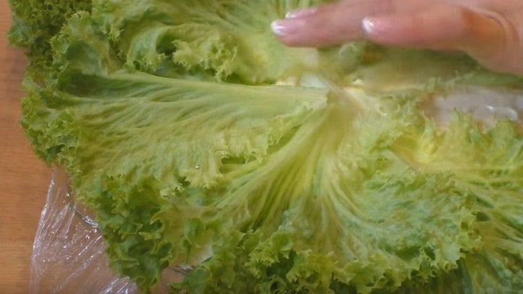 Quitamos la película adhesiva de la ensalada, la cubrimos con hojas de lechuga.