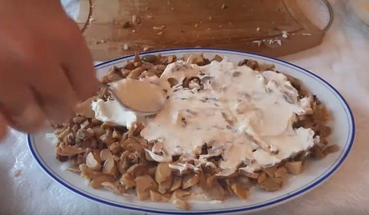 We coat a layer of champignons with mayonnaise.