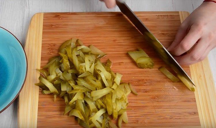 Cortar los pepinos en vinagre en tiras.
