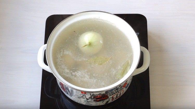 Agregue la cebolla y la hoja de laurel al caldo.