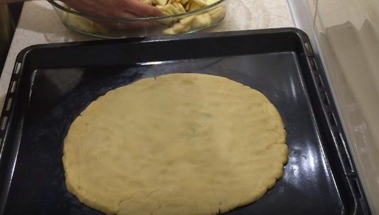 De la masa en una bandeja para hornear formamos una base redonda para el pastel.